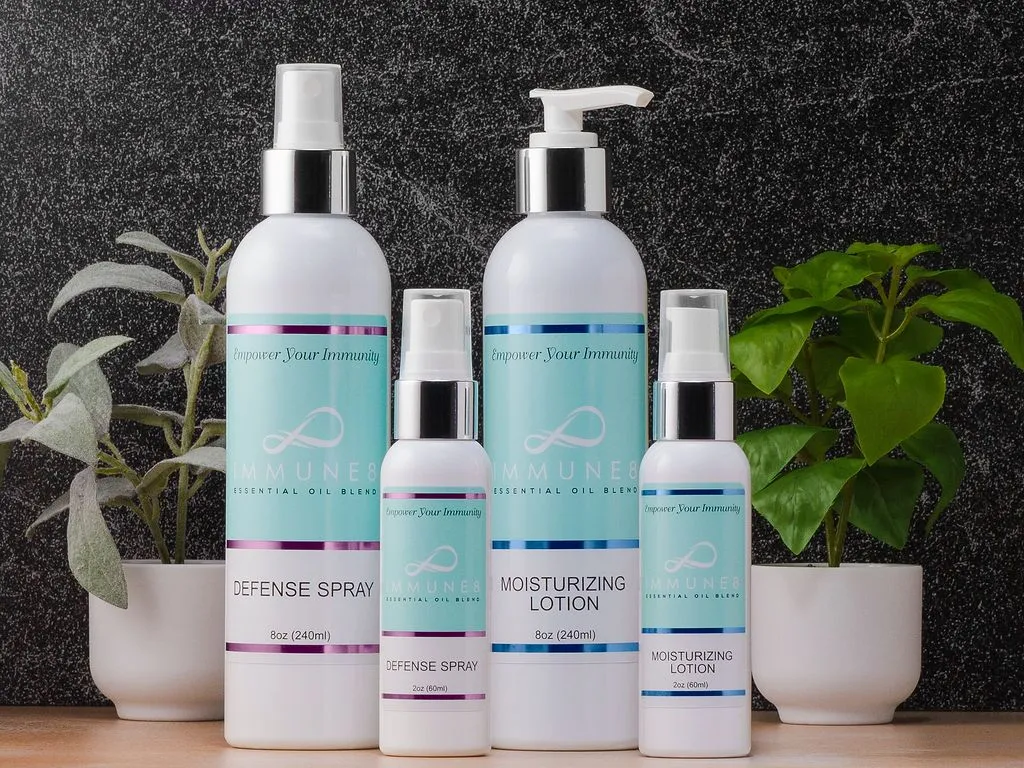 The image showcases four skincare products in elegant white bottles, arranged attractively with green plants, highlighting a clean and soothing aesthetic.