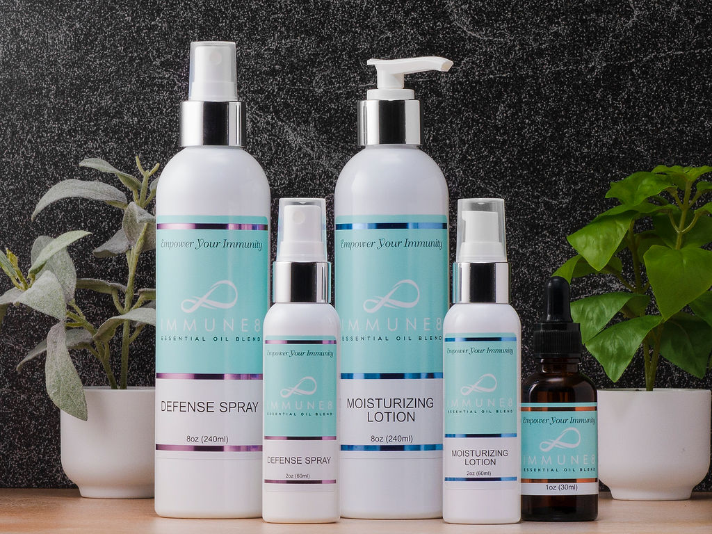 The image showcases a collection of skincare products, including sprays and lotions, displayed alongside potted plants against a textured background.